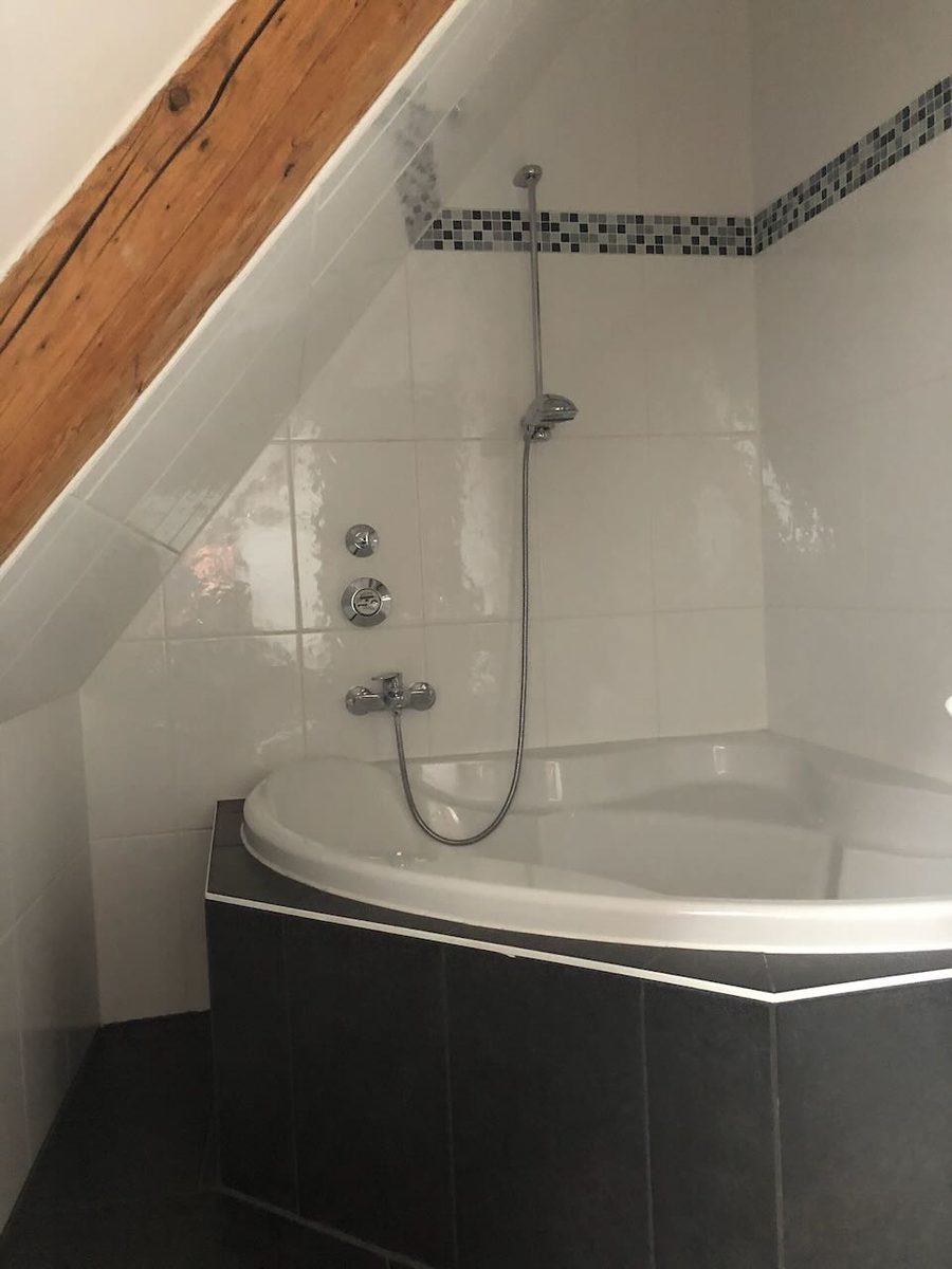 Badezimmer mit Eckbadewanne und dunklen Fliesen