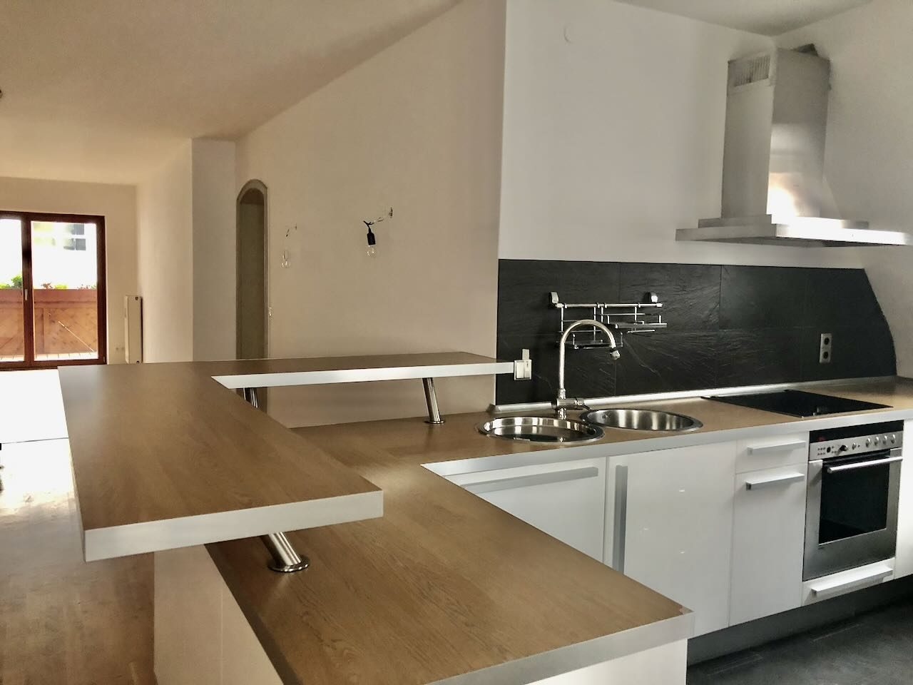Küche mit Holzarbeitsplatte, Theke und Zugang zum Balkon